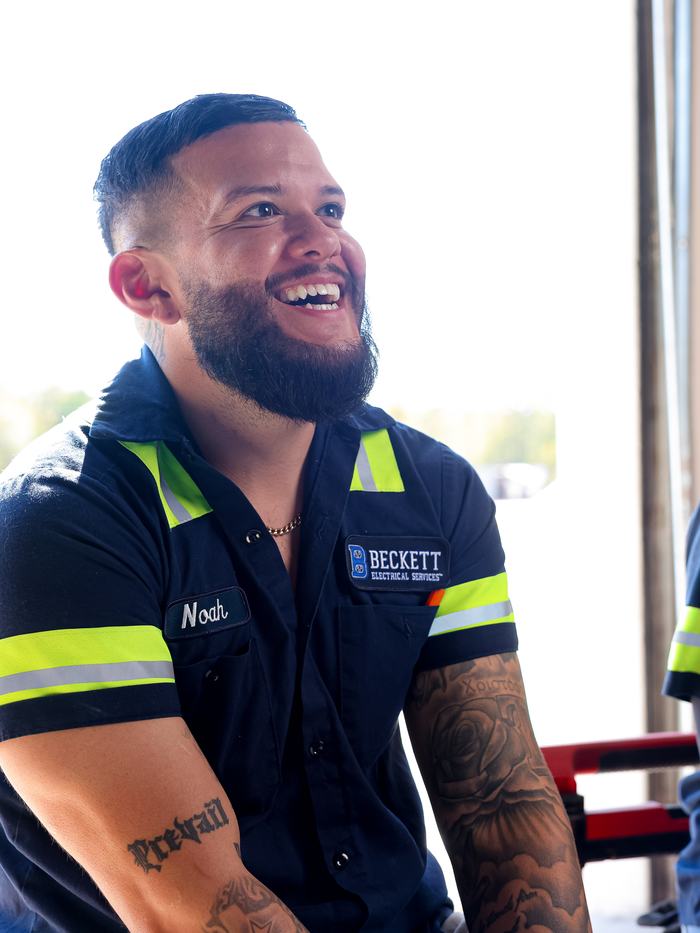 A young electrician in company uniform on the job